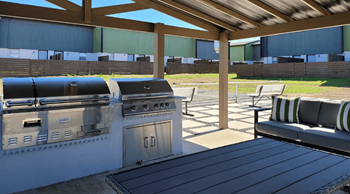 a patio with a grill and a table with chairs